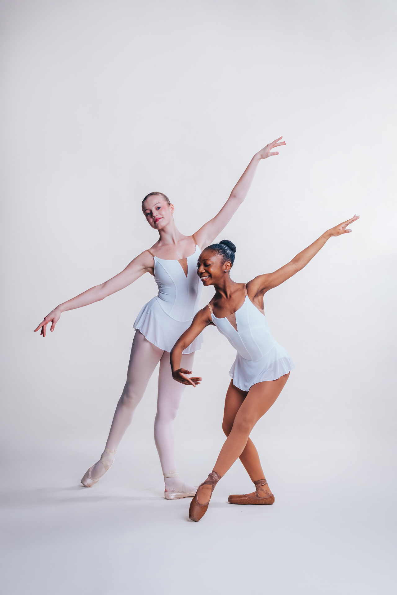 Two ballet dancers in white leotards posing together